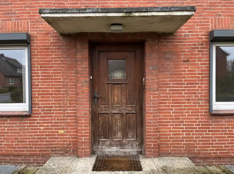Handyfoto der alten Holzhaustür mit Vordach